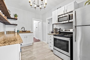 A modern kitchen with white cabinets, a stainless steel refrigerator, a double oven, and a granite countertop. - Belvedere 1 | Modern 3-Bed Flat in Westport (Kansas City)