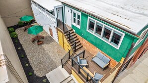 A two-story house with a deck, outdoor seating, and a small garden area.