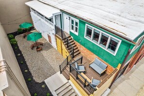 A two-story house with a deck, outdoor seating, and a small garden area.