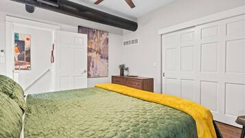 Un dormitorio con una cama, un ventilador de techo, una puerta blanca y una pared con un cartel.