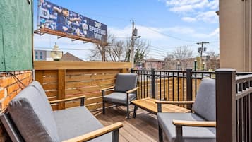 Un área de estar al aire libre con mobiliario de madera y vista panorámica de la ciudad.