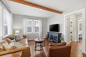 Un salon comprenant un canapé, une table basse, un téléviseur et un meuble.