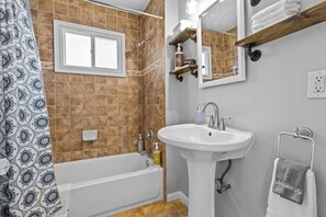 Une salle de bain avec une baignoire, un lavabo, un miroir et un porte-serviettes.