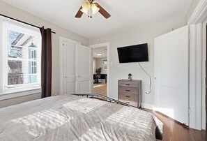 Bedroom includes a mounted Smart TV and convenient dresser storage, making it ideal for longer stays or relaxing movie nights in Kansas City. - Waldo Craftsman - Fenced yard + Walkable to dining (Kansas City)