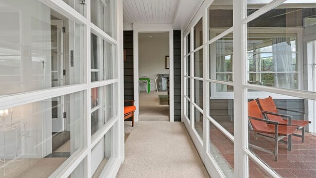 A corridor with glass doors leading to a patio area with outdoor seating.