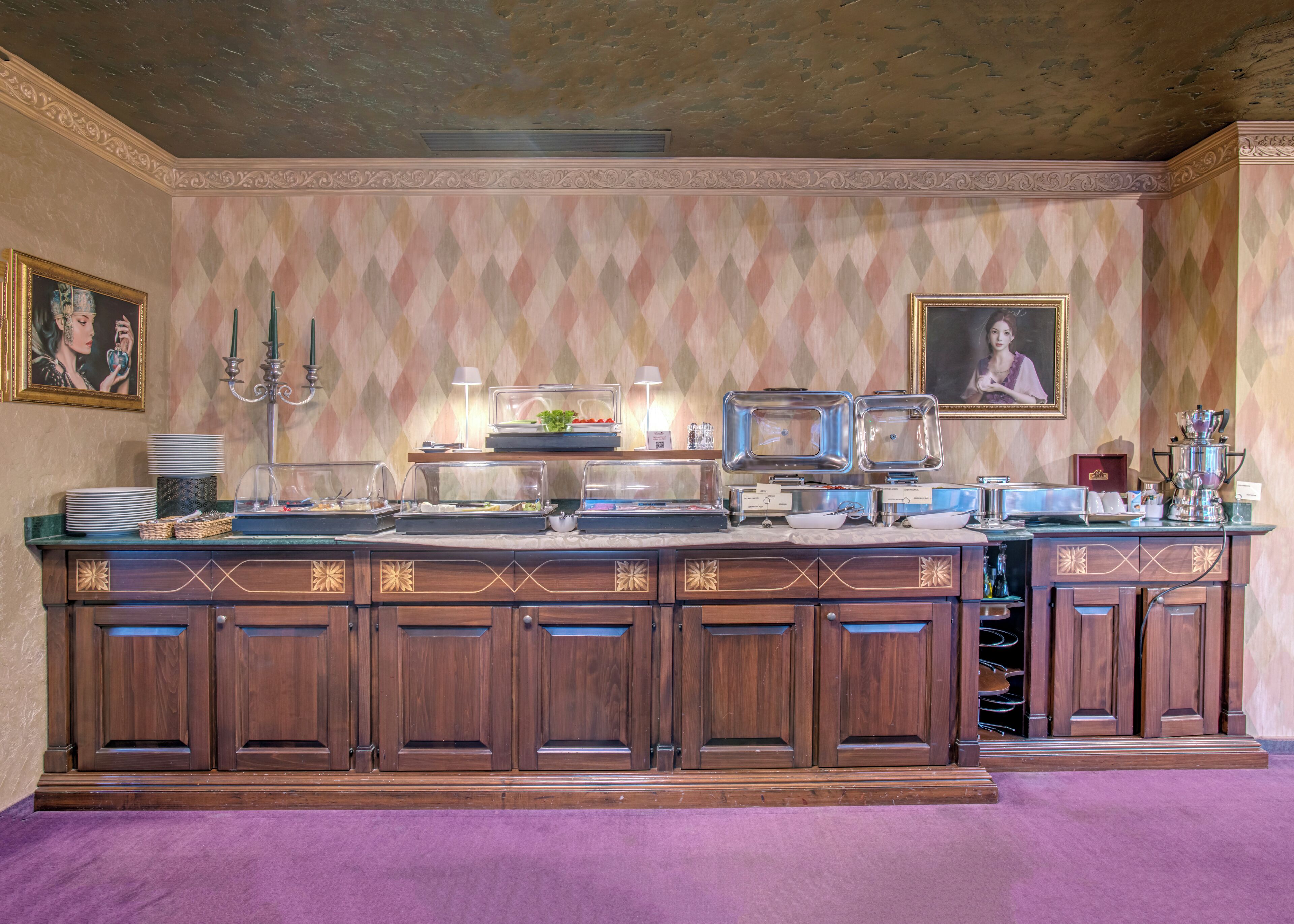 Ein Buffet mit mehreren Servierstationen, einer Kristallleuchter und gerahmten Kunstwerken an den Wänden.