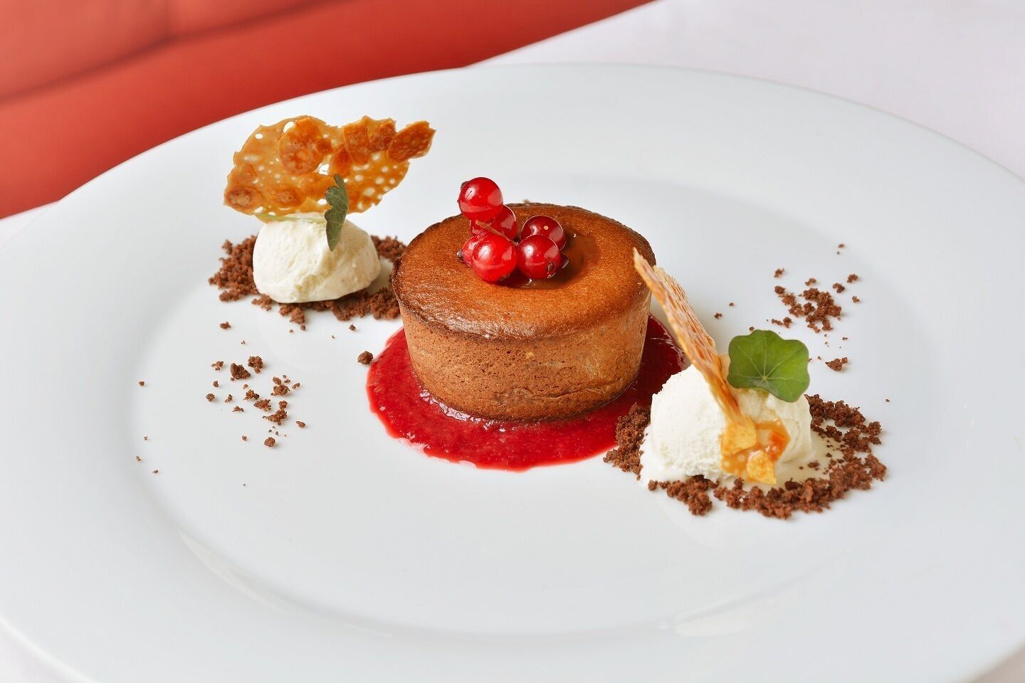 Un plato de postre con un pastel en capas, helado y compota de frutos rojos.