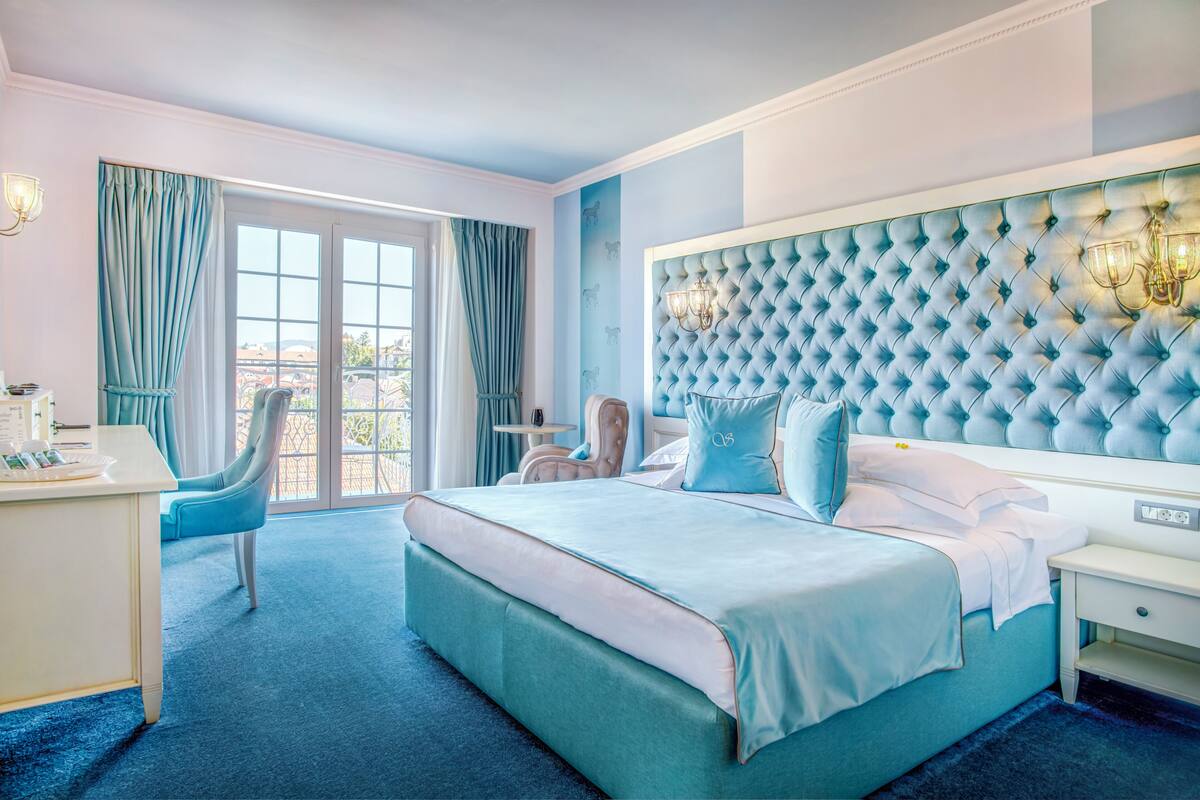 A bedroom with a large bed, a desk, and a chair.