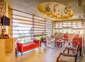 Amplia sala de estar con grandes ventanales, un sofá rojo, una mesa de centro de madera y varios lámparas colgantes.