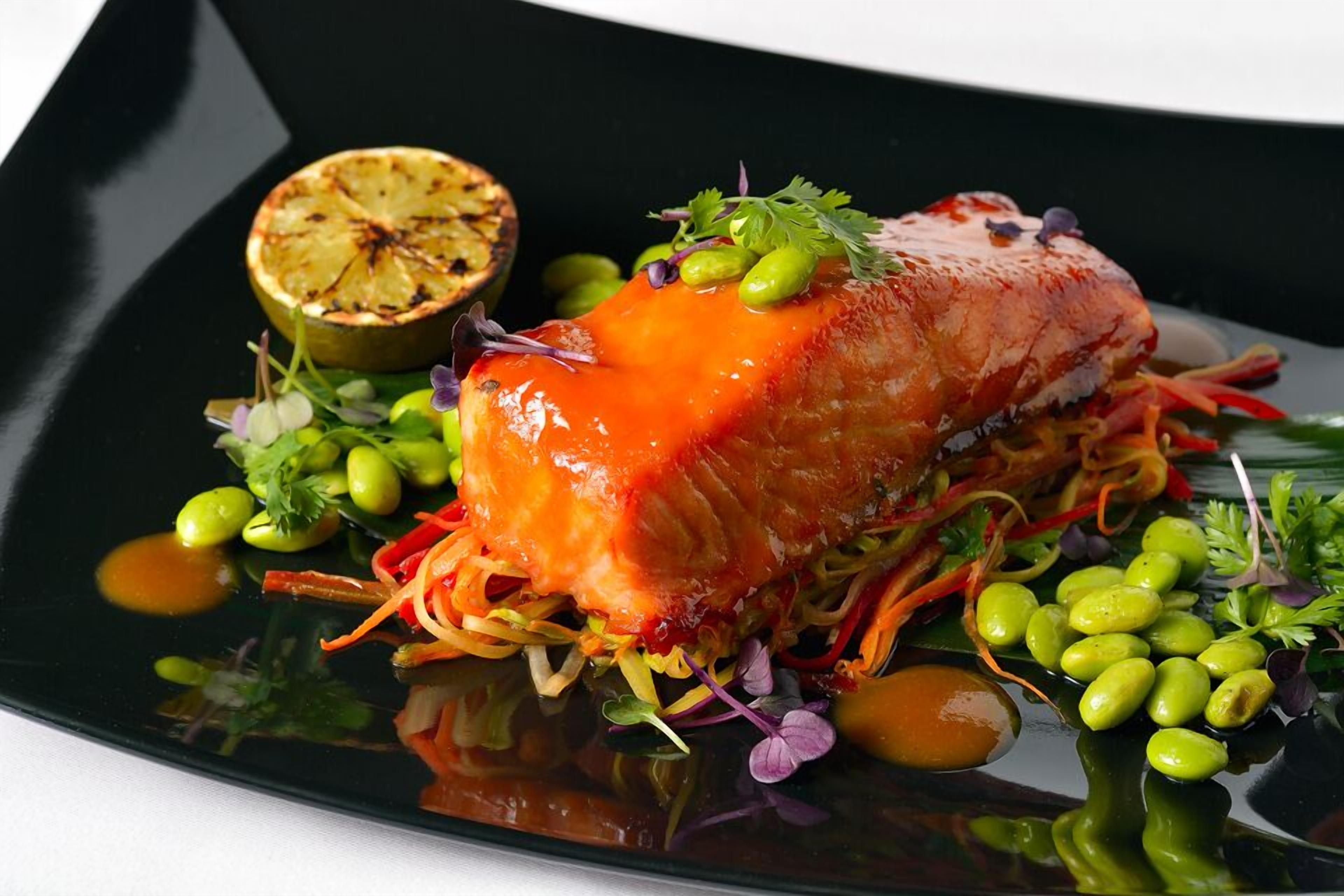 Ein Teller mit Lachs, Gemüse und einer halben Zitrone.