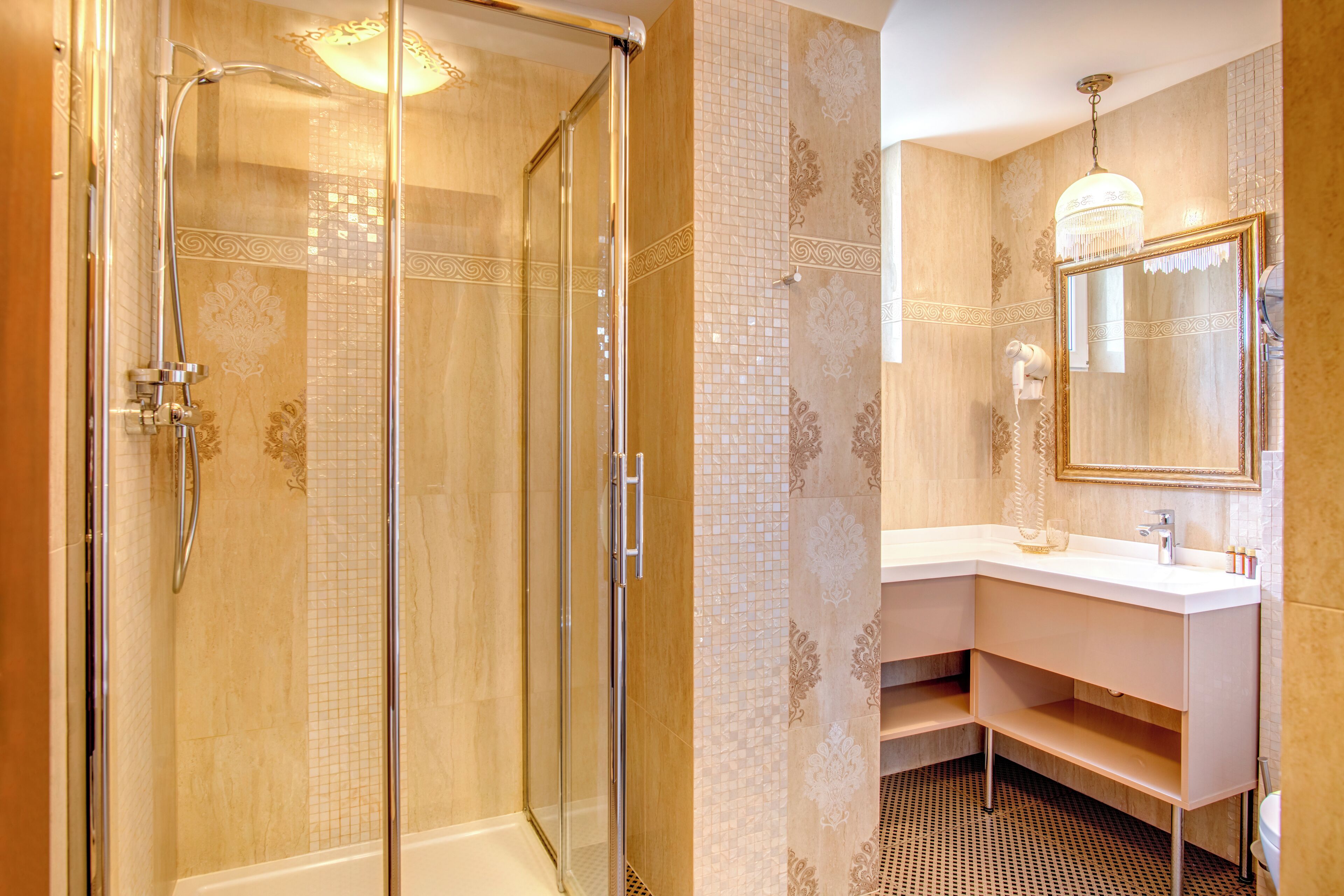 A modern bathroom with a glass-enclosed shower, a white vanity with a mirror, and patterned wall tiles.