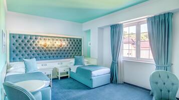 A hotel room with a tufted headboard, a bed, a desk, a chair, and a window with curtains.