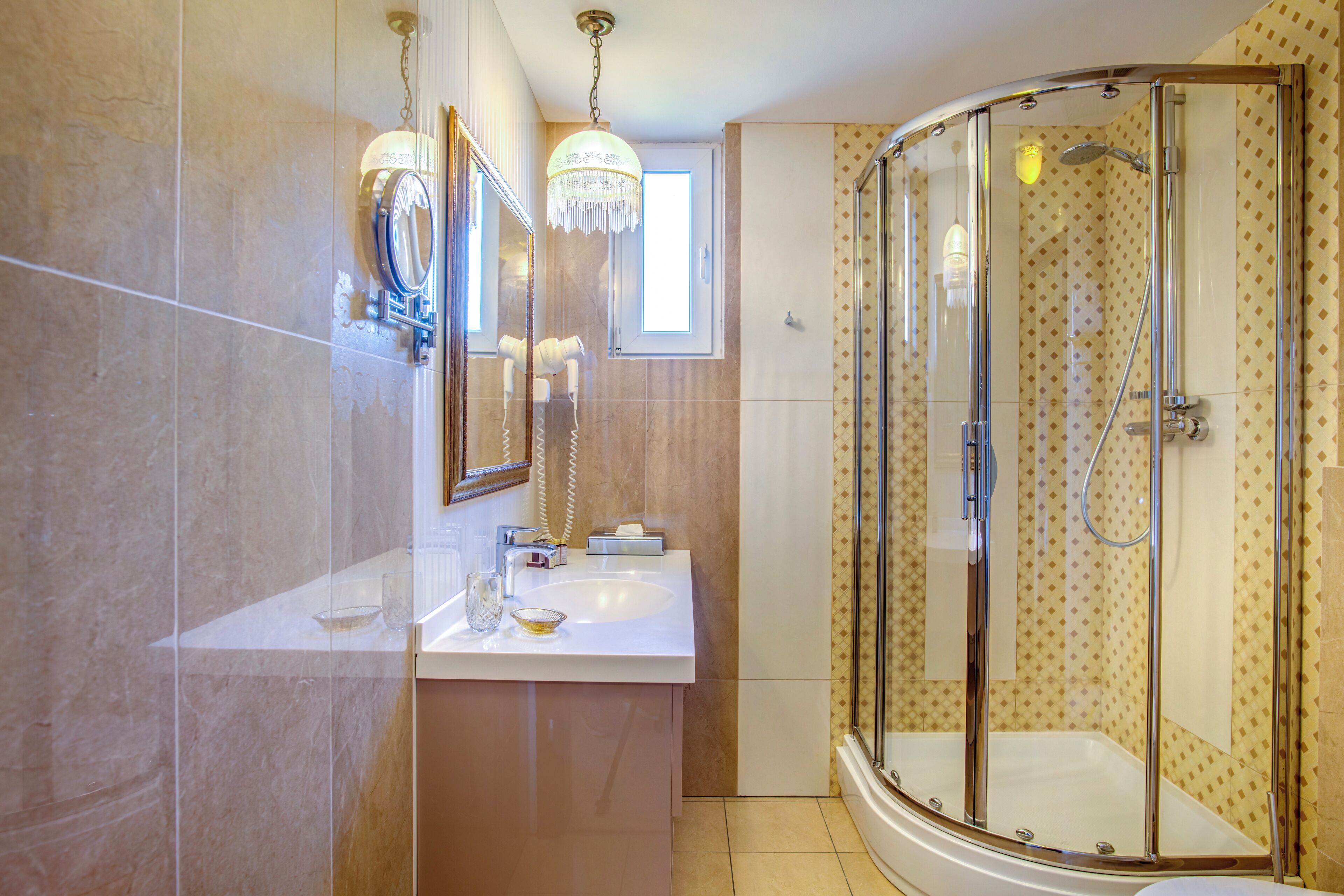 A modern bathroom with a glass-enclosed shower, a vanity with a mirror, and a small window.