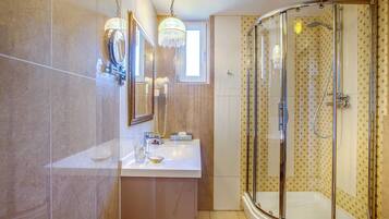 A modern bathroom with a glass-enclosed shower, a vanity with a mirror, and a small window.