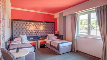 Una habitación de hotel con una cama grande, una cama más pequeña, un escritorio y una silla.