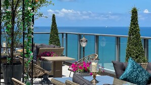 Een terras met rieten meubilair, een tafel met bloemen en uitzicht op zee.
