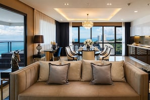 Una habitación de hotel moderna con un sofá grande, una zona de comedor y vistas a la ciudad.