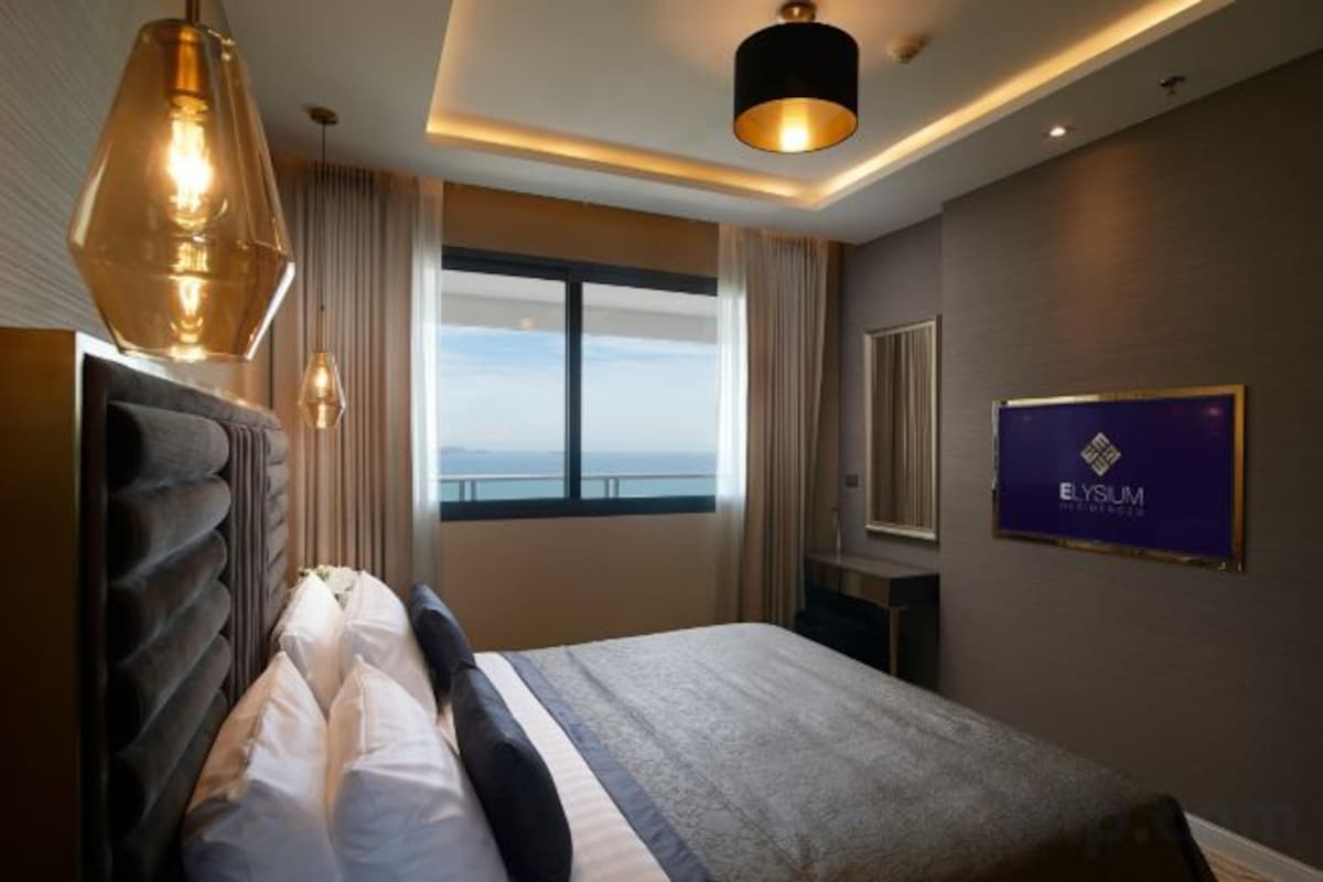 Une chambre d’hôtel avec un grand lit, une vue sur la mer et un panneau accroché au mur.
