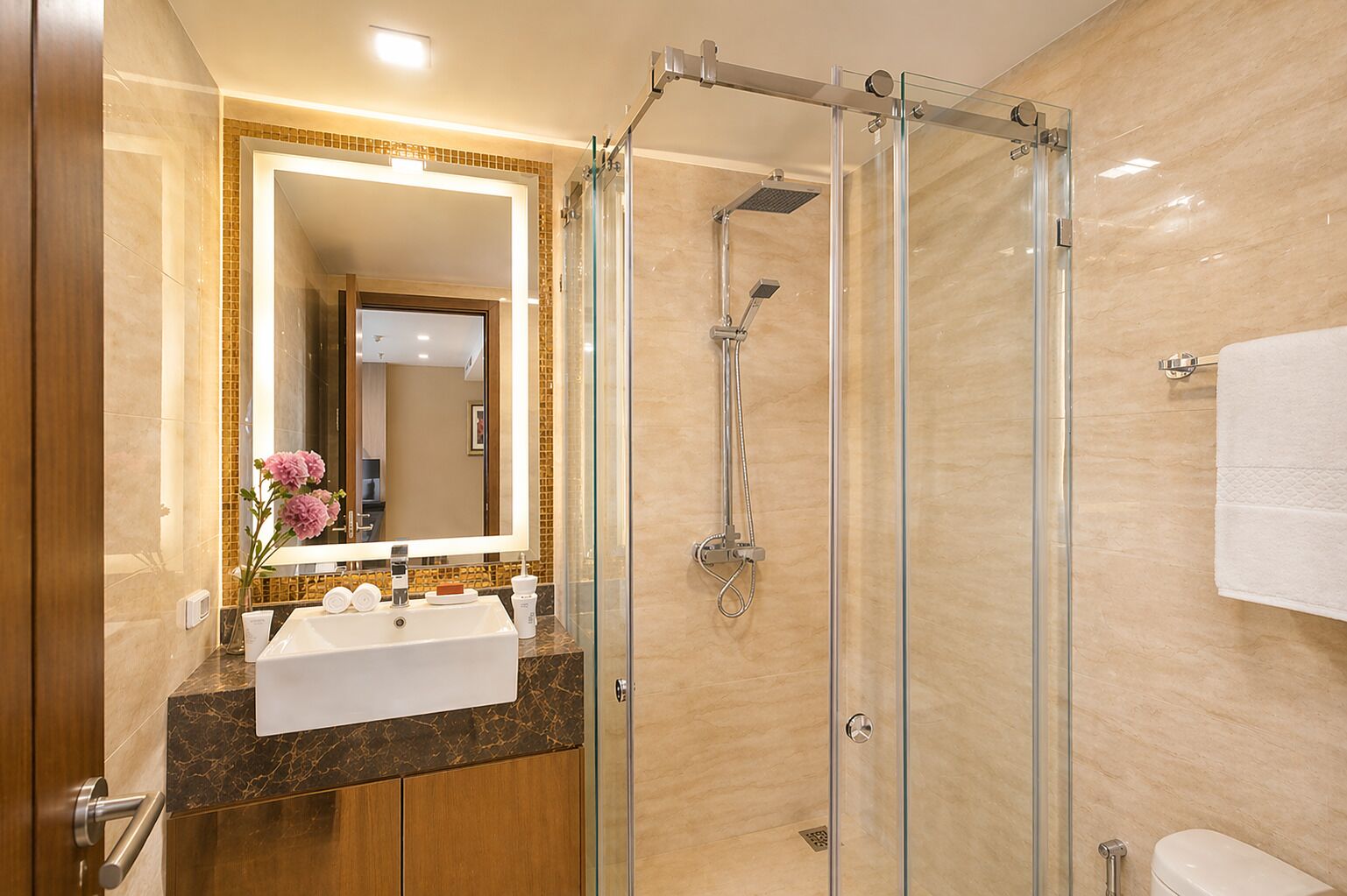 A modern bathroom with a glass-enclosed shower, a large mirror, and a marble countertop.