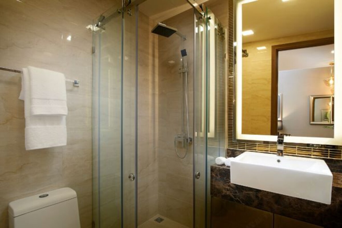 A modern bathroom with a glass-enclosed shower, a white sink, and a marble countertop.