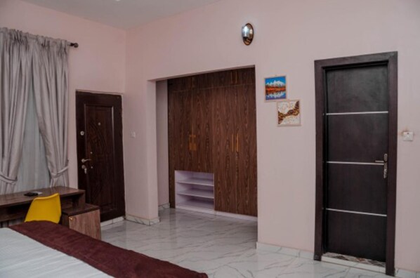 A hotel room with a bed, a desk, a chair, a wardrobe, and a door.