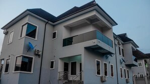Uma casa moderna de dois andares com varanda, antenas parabólicas e escadaria que leva à entrada.