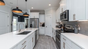 A modern kitchen with white cabinetry, stainless steel appliances, and pendant lighting. - 34 Luxury Beach House w/ Pool & Hot Tub | FirePit | Fenced Yard | Sleeps 24 (Hilton Head Island)