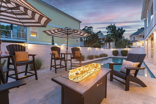 Un patio al aire libre con piscina, zona de estar e iluminación ambiental.
