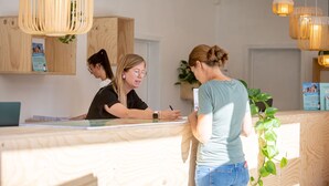 Een receptiegedeelte met houten kasten, een receptiebalie en hangende pendelverlichting.