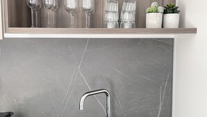 Een keuken met een zwart spoelgedeelte, een houten plank erboven en een marmeren achterwand.