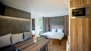 Een moderne hotelkamer met een bed, een houten tafel, een zithoek en een inbouw-magnetron.