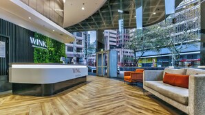 Un espace d’accueil au design moderne, doté d’un parquet en bois disposé en chevrons, d’un comptoir de réception et d’un coin salon avec un canapé et des fauteuils.