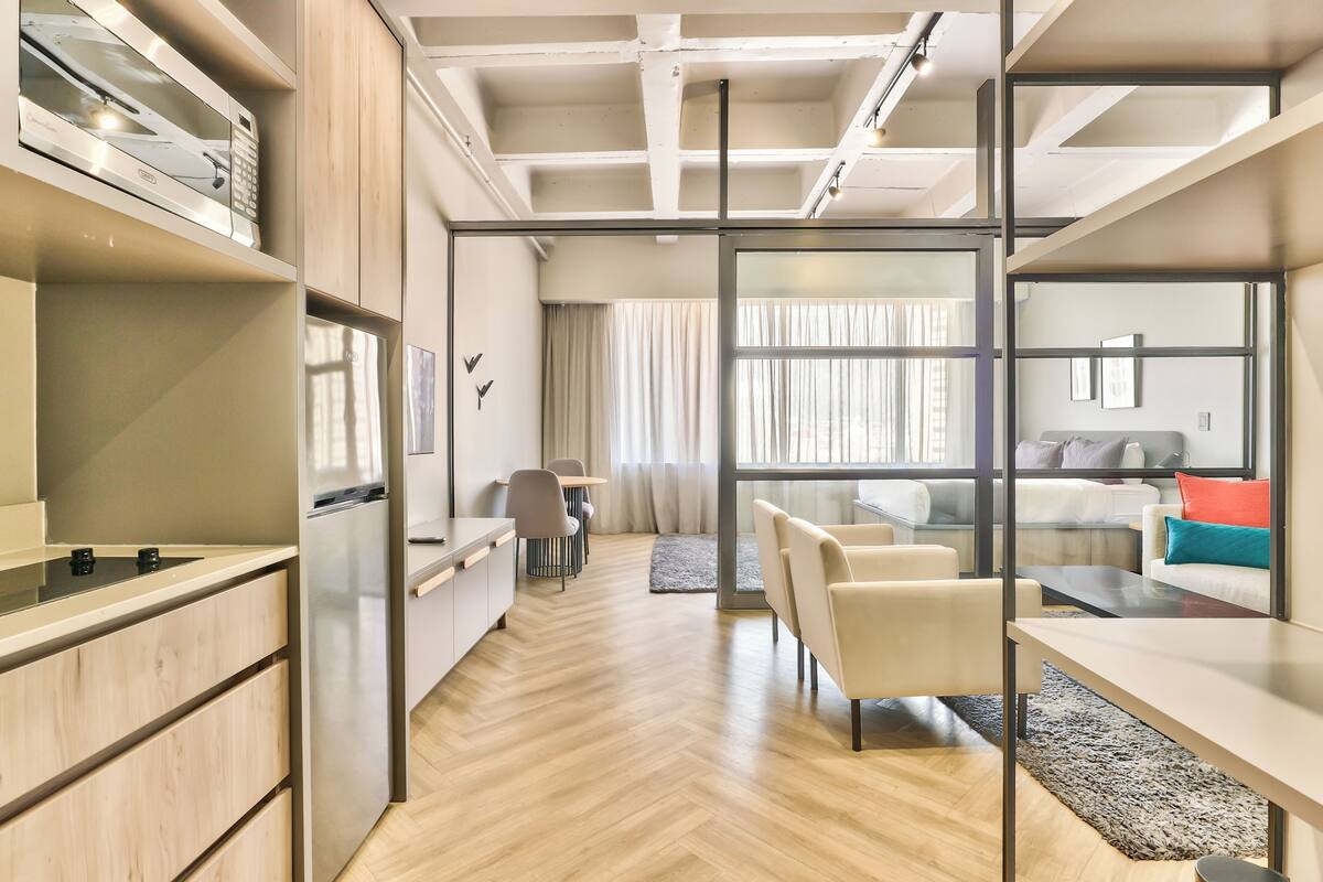 A modern kitchen with a built-in microwave, a dining area with a table and chairs, and a living space with a sofa and a coffee table.