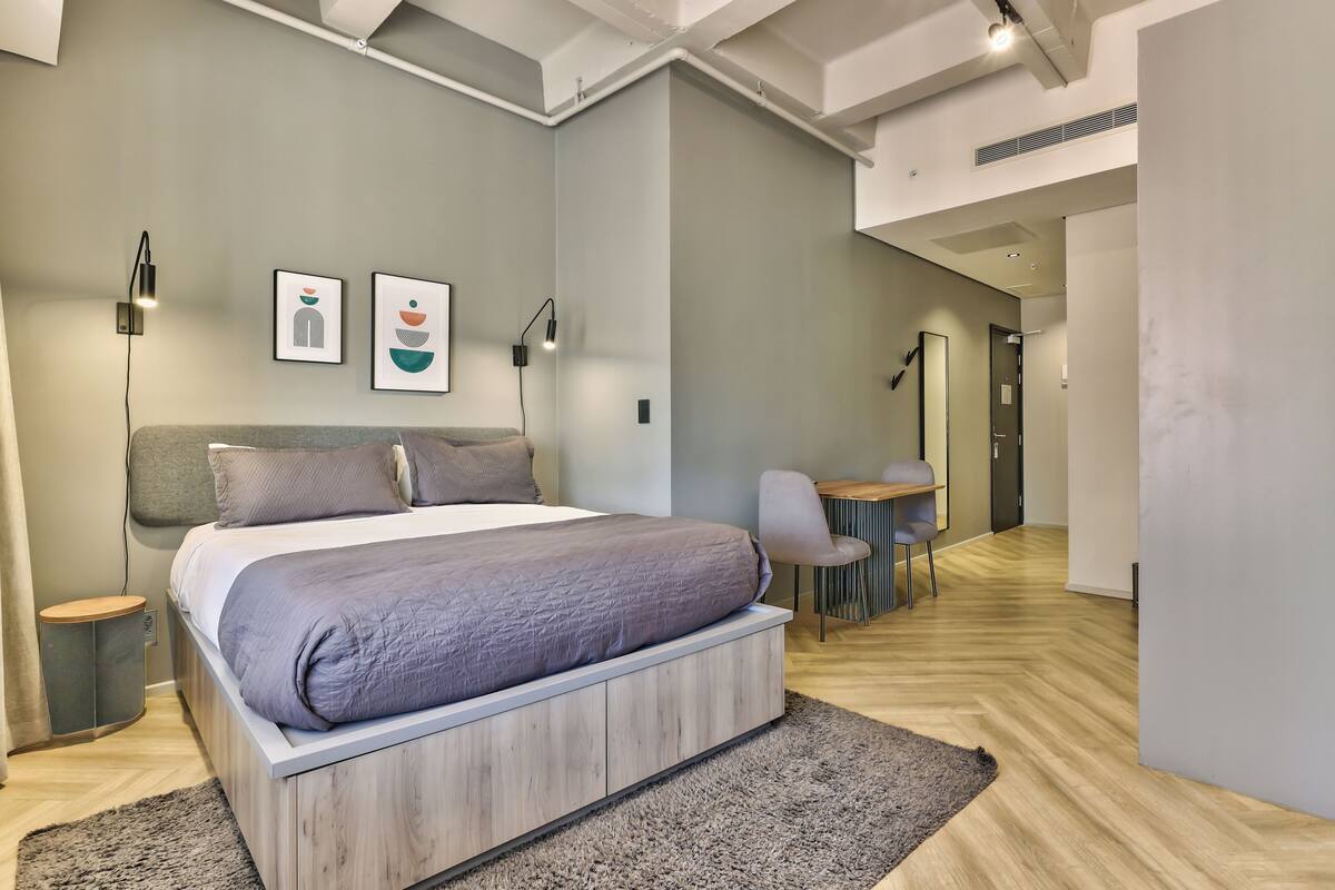 A modern bedroom with a large bed, bedside tables, a desk, and a chair.