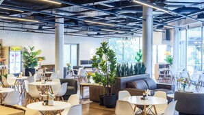 Un espace de détente moderne avec des tables rondes, des chaises blanches et différents types de sièges, notamment des canapés et un divan.