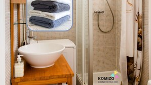 Een badkamer met een wastafel, een douche en een handdoekhouder.