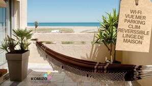 Een hangmat onder een pergola met uitzicht op strand en zee.