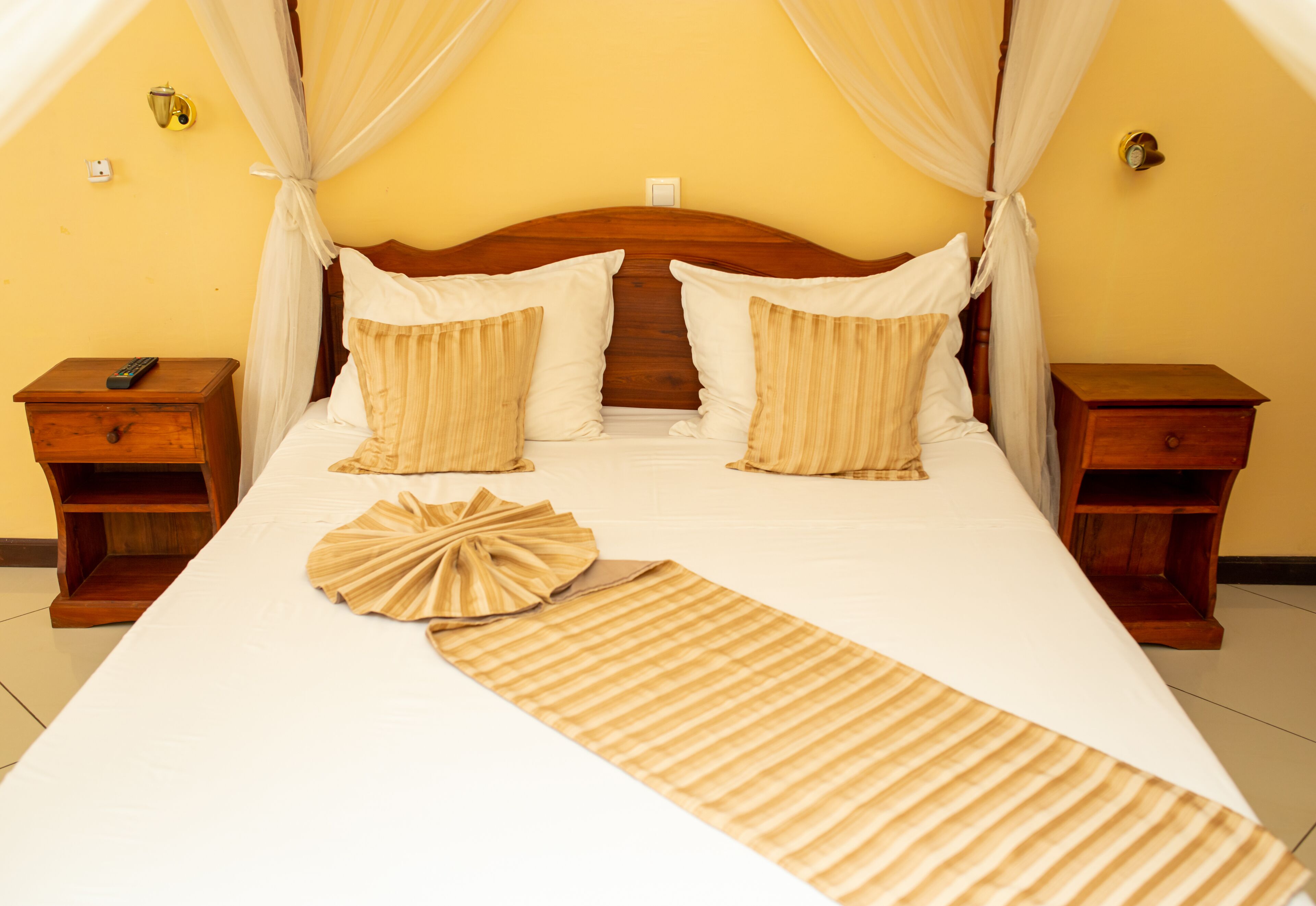 A bed with a canopy, two bedside tables, and a decorative pillow.