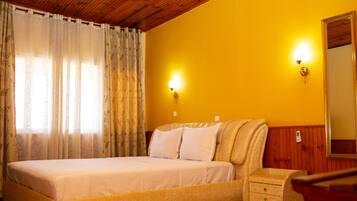 A bedroom with a bed, a nightstand, a mirror, and two wall-mounted lights.