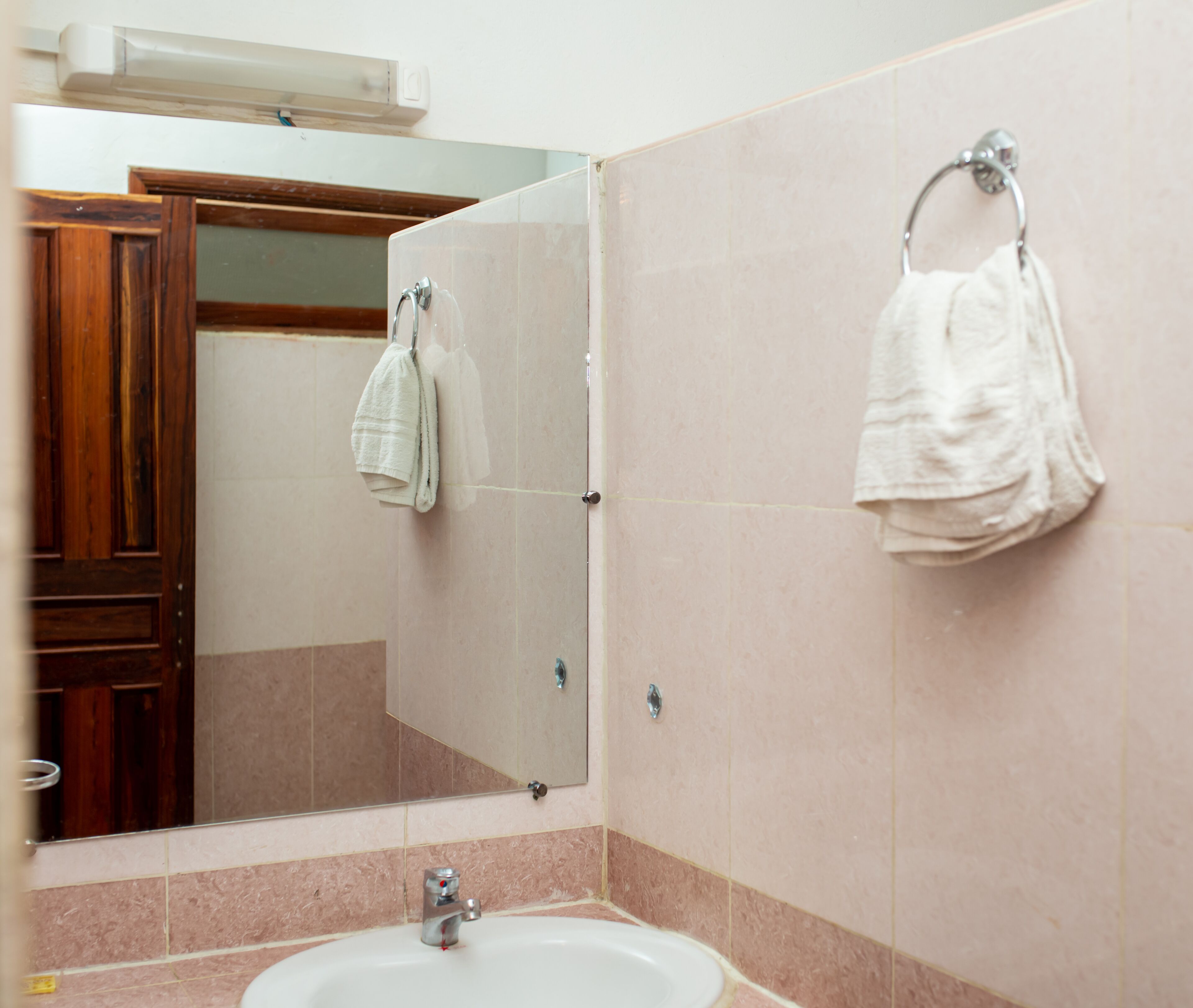 A bathroom with a sink, mirror, and two towels hanging on hooks.