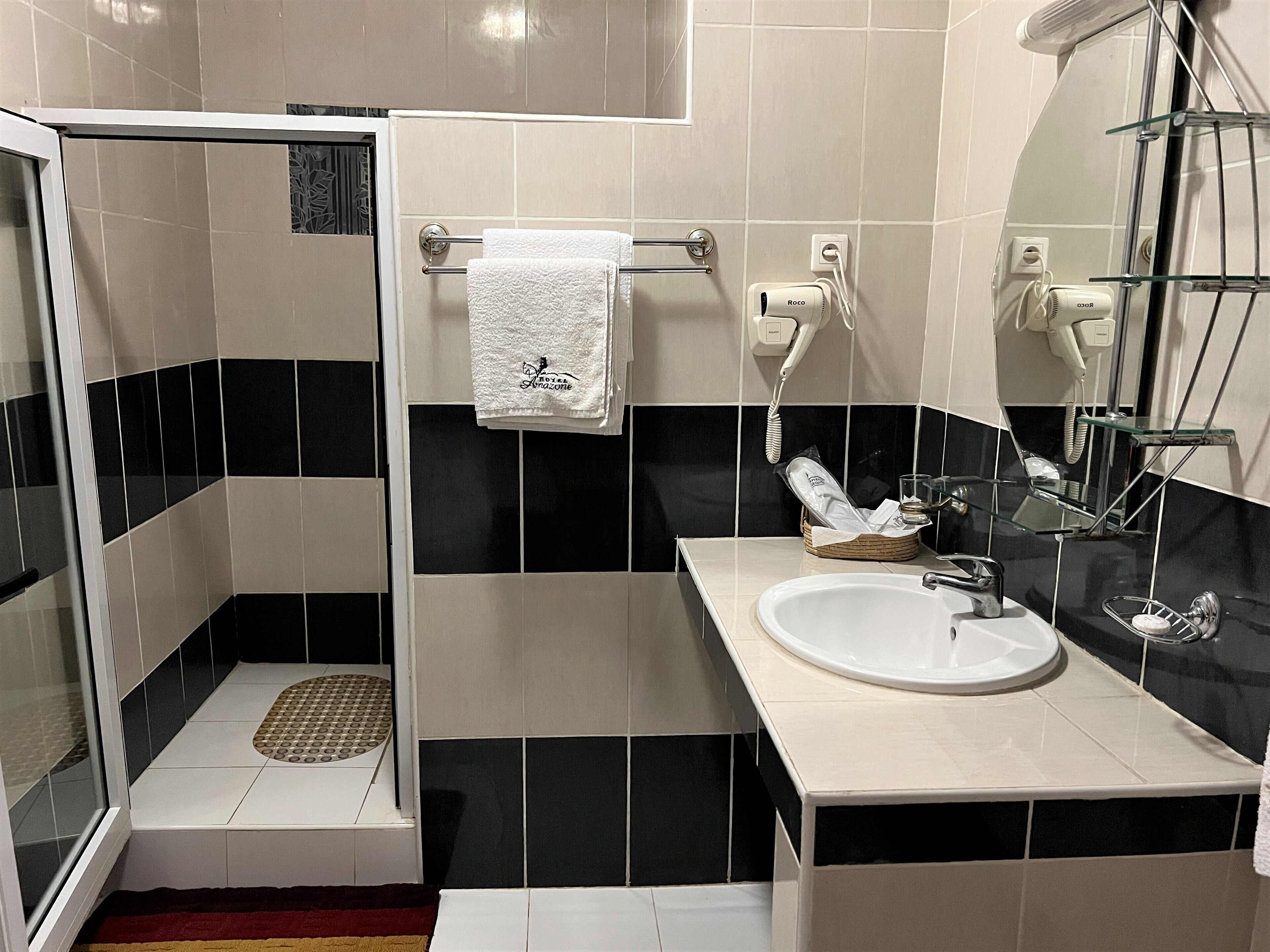 Un baño con ducha, lavamanos y espejo.