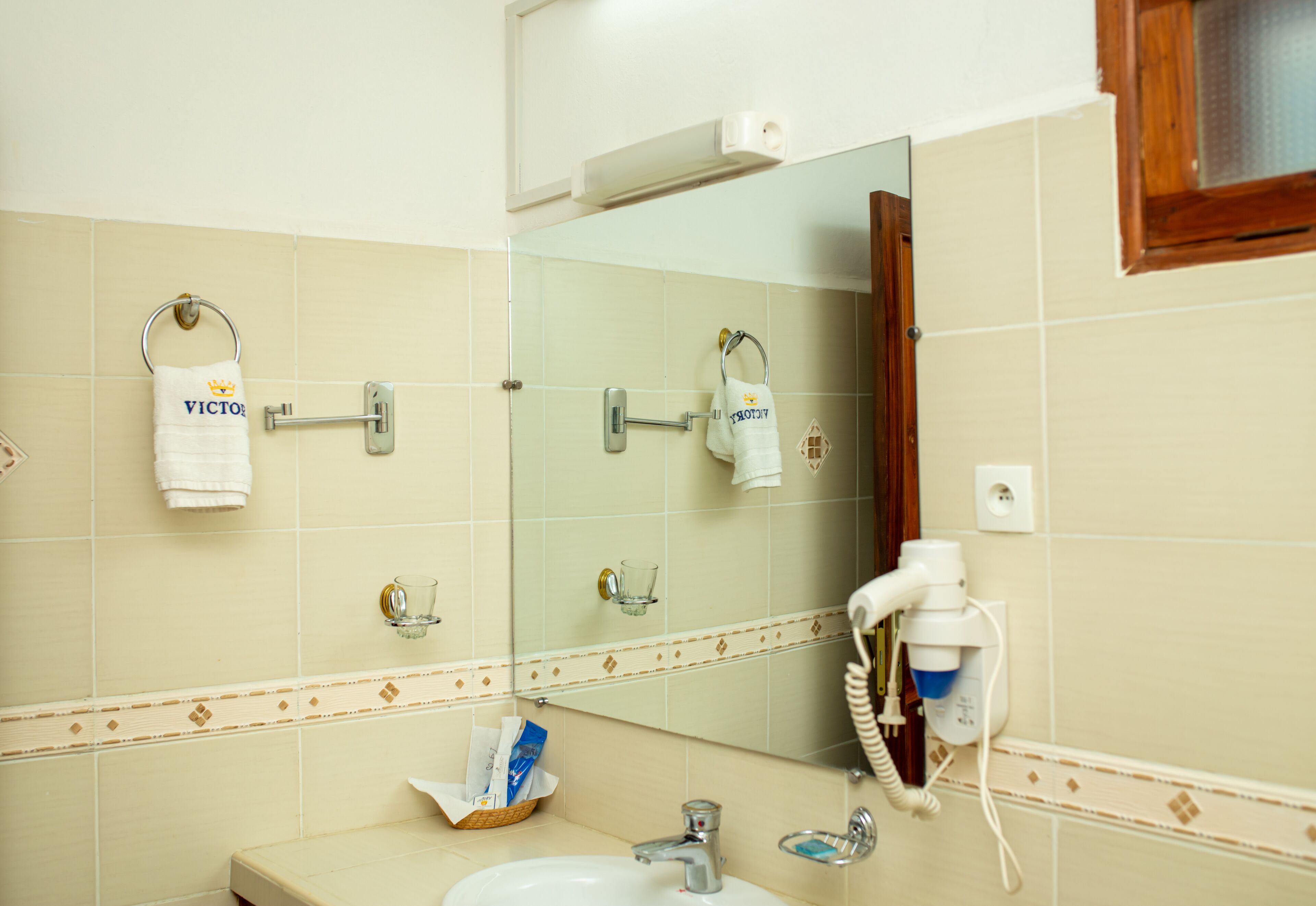 Ein Badezimmer mit Waschbecken, Spiegel, Handtuchhalter und Fön.