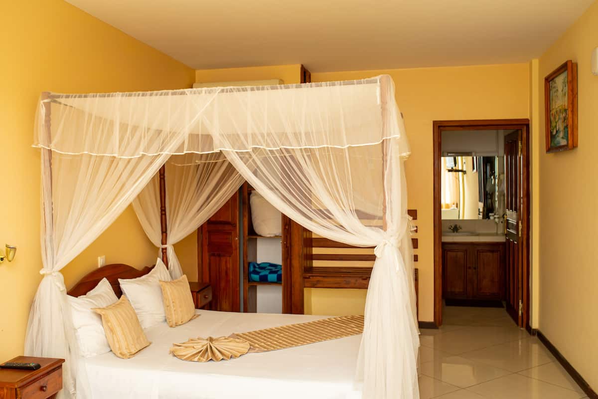 A bedroom with a four-poster bed, a bedside table, and a nightstand.