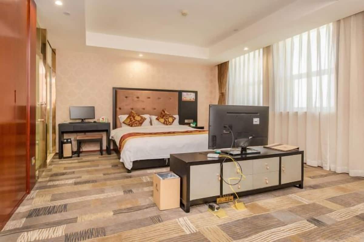 Ein Hotelzimmer mit einem Bett, einem Schreibtisch mit Computer, einem Fernseher und einem Schrank.