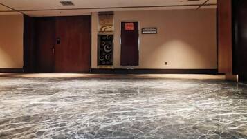 A hotel lobby with a marble floor, a reception desk, and a door with a sign.