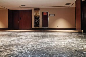 Un vestíbulo de hotel con piso de mármol, un mostrador de recepción y una puerta con un letrero.