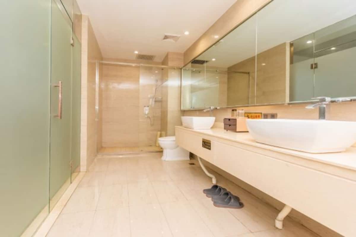 Ein modernes Badezimmer mit einem großen Spiegel, zwei Waschbecken und einer Duschkabine.
