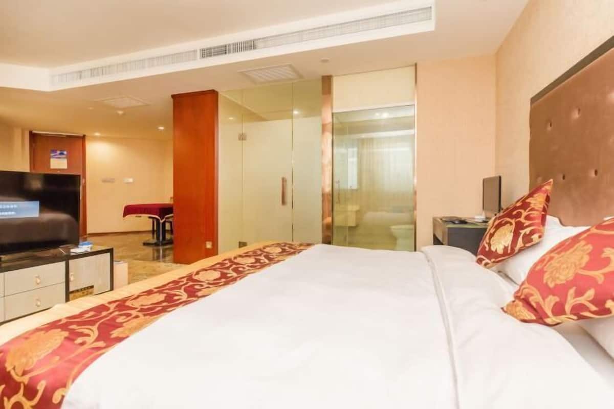 Ein Hotelzimmer mit Bett, Fernseher, Schreibtisch und Bad.