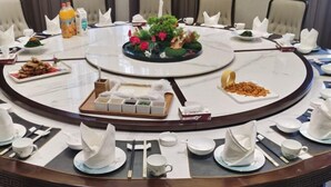 Una mesa redonda de comedor con un arreglo floral en el centro, rodeada de sillas.