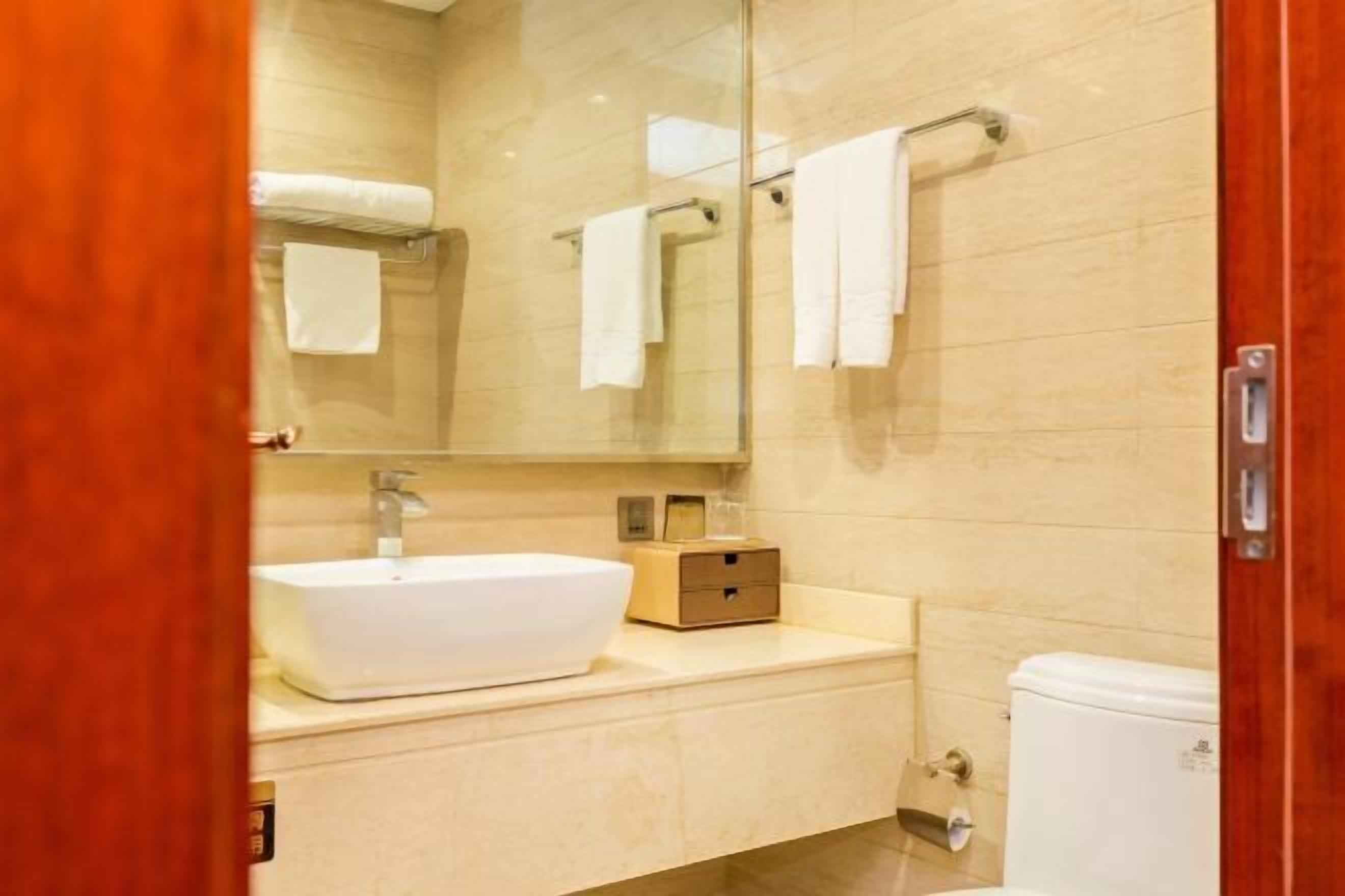 Ein Badezimmer mit einem weißen Waschbecken, einem Spiegel, einem Handtuchhalter und einer Toilette.